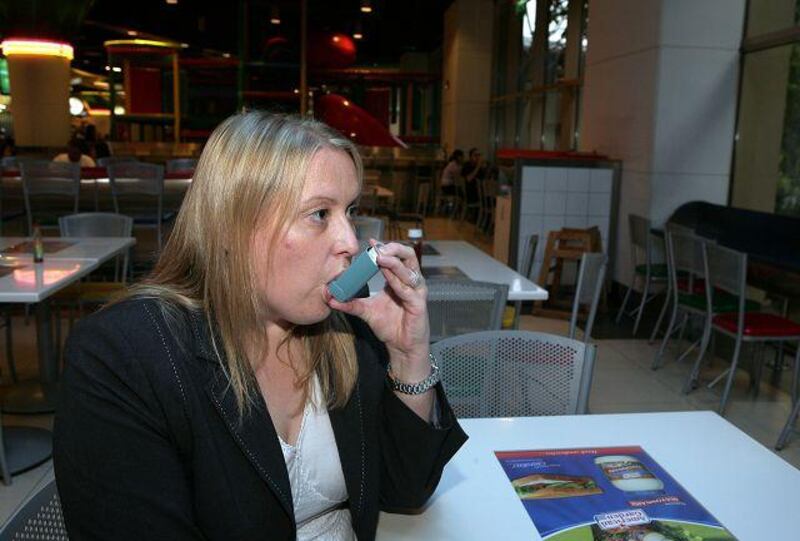 Stacey Fell, a business development manager from the UK, shows how she uses an inhaler when suffering an asthma attack, at a food court in Mall of Emirates.