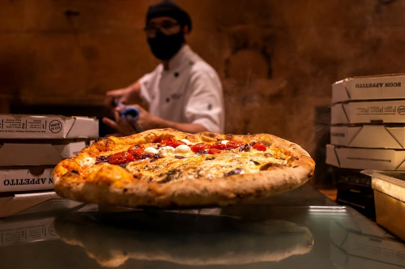 RIO DE JANEIRO, BRAZIL - SEPTEMBER 23: A staff member wearing a face mask prepares a pizza at Mamma Jamma pizzeria in the Botafogo neighborhood on September 23, 2020 in Rio de Janeiro, Brazil. Establishments are adopting preventive measures against the spread of the coronavirus (COVID-19) according to a protocol for the reopening of bars and restaurants in the city of Rio de Janeiro. (Photo by Bruna Prado/Getty Images)