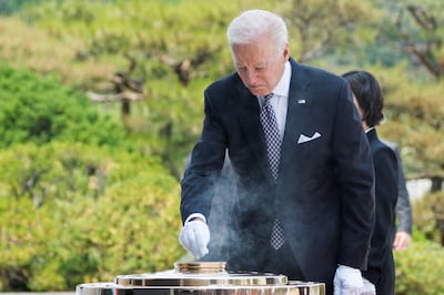 US  President Joe Biden places incense in the memorial flame during a wreath-laying ceremony at the Seoul National Cemetery.  Reuters