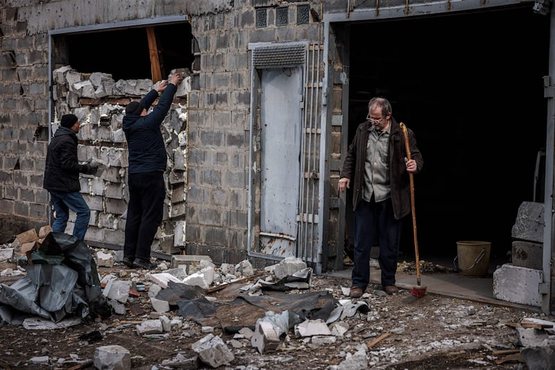 Residents try to strengthen the wall of a house damaged by recent shelling, on the outskirts Kyiv. AFP