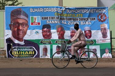 A cyclist drives pasts a campaign poster for President Muhammadu Buhari in a street after the postponement of the presidential election in Kano, Nigeria February 17, 2019. REUTERS/Luc Gnago