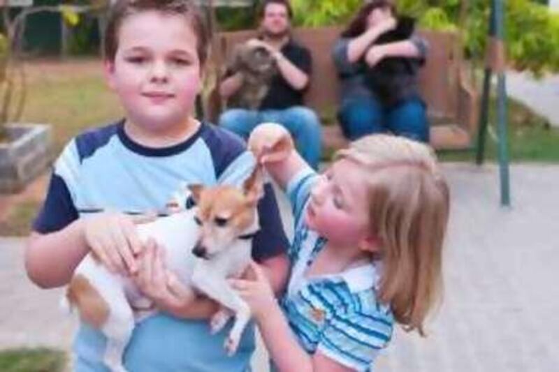 Nine year old Keagan(L) and  five year old Kyarha Kaltwasser become familiar with their newly adopted miniature terrier "Dusty" while their Mom & Dad, Ilze & Willem, do the same with the two Persian cats they adopted at the Dubai Animal Rescue Center in Barsha on Tuesday, Aug. 09, 2010. Photo: Charles Crowell fr The NAtional