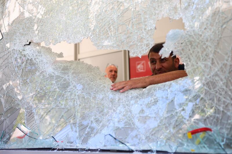 Cleaning and security contractors examine a damaged window of a Caisse d'Epargne bank in the centre of Marseille in France. AP