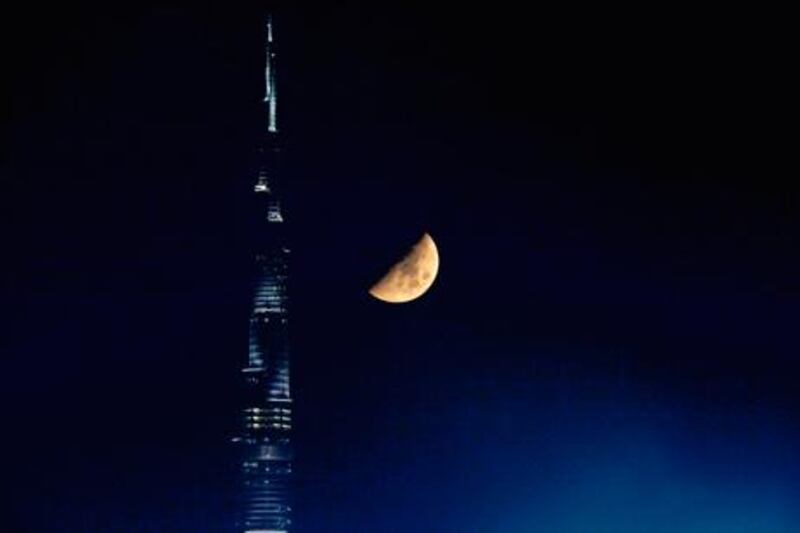 The moon hangs low next to the Burj Khalifa. Astronomers now say they have predicted when this year's Ramadan Crescent will form. The National / Andre Forget