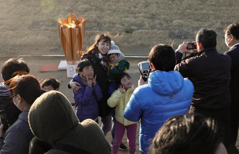 A family takes a selfie with the Olympic flame on a cauldron displayed at Ishinomaki Minamihama Tsunami Recovery Memorial Park. EPA