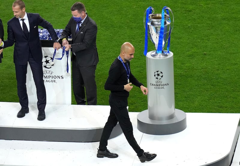 Manchester City manager Pep Guardiola with the runners up medal as he walks past the trophy. PA