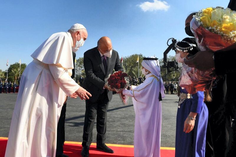 Pope Francis receives a gift as he arrives at Iraq's Presidential Palace. Office of the President