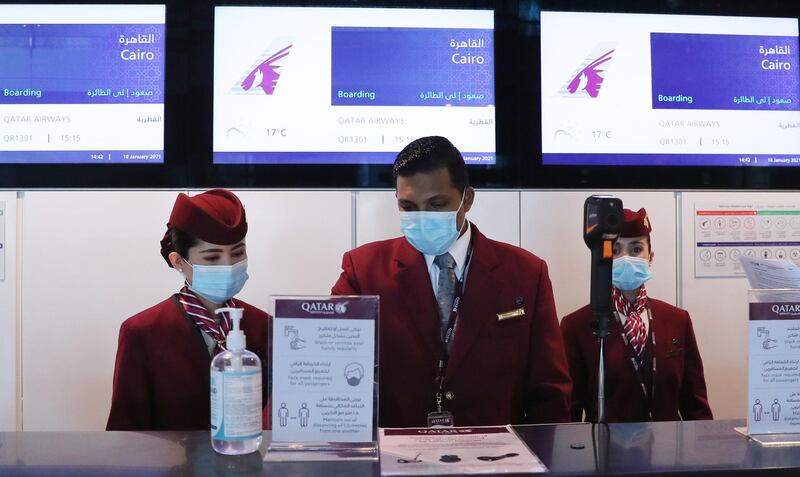 Qatar Airways employees wait at the boarding counter ahead of the first flight bound for Cairo after the resumption of flights between Qatar and Egypt, at Qatar's Hamad International Airport near the capital Doha on January 18, 2021. Egypt reopened its airspace to Qatari flights on January 18 following a thaw in relations between Doha and a Saudi-led bloc. Egypt in June 2017 joined Saudi Arabia, the United Arab Emirates and Bahrain in cutting ties with Qatar, accusing it of being too close to Iran and backing the Muslim Brotherhood, seen by Cairo and its Gulf allies as a "terrorist" group. Qatar has denied the charges. / AFP / KARIM JAAFAR
