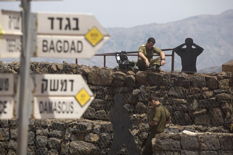 GOLAN HEIGHTS - MAY 10:  (ISRAEL OUT)  Israeli soldier is seen next to a signs pointing out distance to different cities on Mount Bental next to the Syrian border on May 10, 2018 in the Israeli-annexed Golan Heights. Some 20 rockets were fired at Israeli military bases by Iranian forces from southern Syria just after midnight on Thursday, sparking the largest ever direct clash between Jerusalem and Tehran, with Israeli jets targeting numerous Iranian-controlled sites across Syria. On Monday  U.S. President Donald Trump pulled out of the Iran deal.  (Photo by Lior Mizrahi/Getty Images)