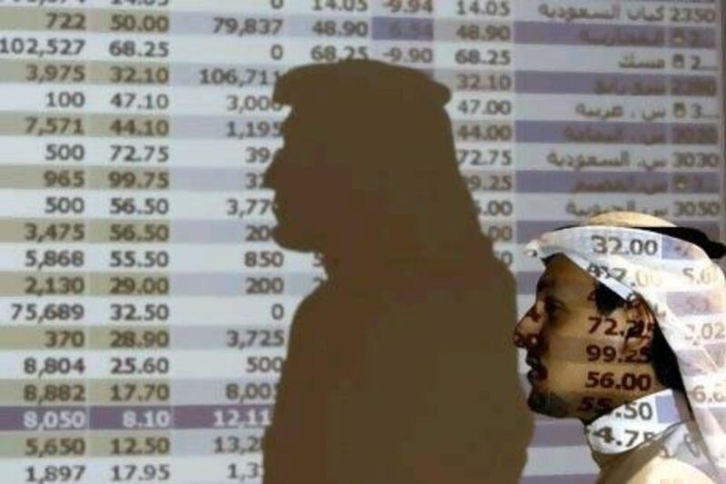 A Saudi trader walks past a stock market monitor in Riyadh.