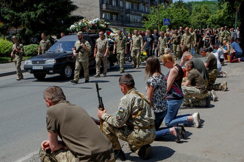Residents kneel during a funeral procession for senior lieutenant Vasyl Herych, 31, of the 15th Separate Mountain Assault Battalion, who was killed in Perechyn, Ukraine. Reuters