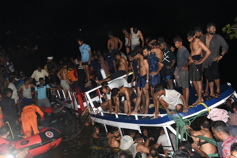 In this photograph taken on May 7, 2023, people carry out rescue operation at the site of a boat accident in Tanur, in Malappuram district of India's Kerala state.  - At least 20 people died when a double-decker tourist boat capsized in India's southern state of Kerala late on May 7, authorities told local media.  (Photo by AFP)