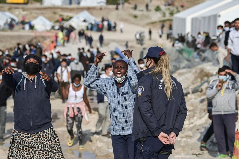 TOPSHOT - African migrant women shout "freedom" inside the new refugee camp of Kara Tepe in Mytilene, on Lesbos, on March 29, 2021. EU home affairs commissioner Ylva Johansson pledged 276 million euros ($326 million) of EU money for new camps on the islands of Lesbos, Chios, Samos, Kos and Leros, where nearly 14,000 migrants are hosted, during a visit to the island of Lesbos, which hosts more than 8,000 asylum seekers. She said it was imperative to find "new political solutions" to share the burden between EU states. / AFP / ARIS MESSINIS
