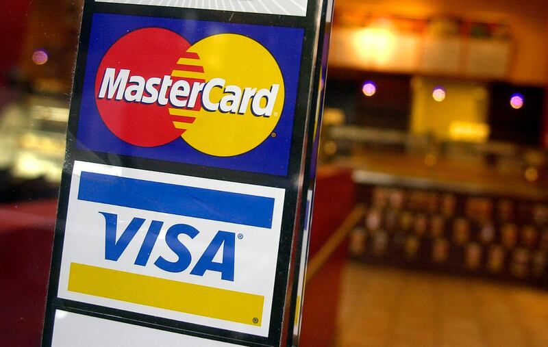 FILE - This April 22, 2005, file photo, shows logos for MasterCard and Visa credit cards at the entrance of a New York coffee shop. Visa and Mastercard are dropping out of Facebookâ€™s Libra project, a potentially fatal blow to the social networkâ€™s plan for a worldwide digital currency, Friday, Oct. 11, 2019.  (AP Photo/Mark Lennihan, File)