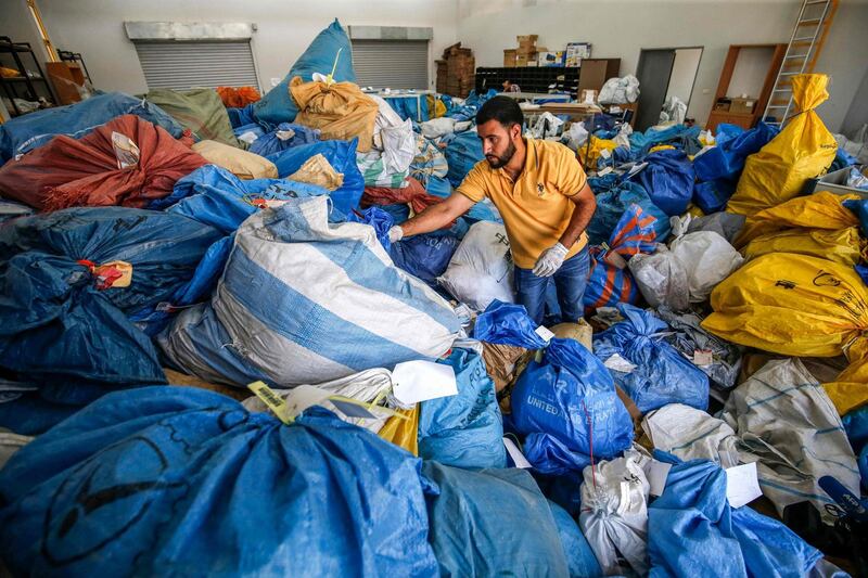 A Palestinian postal worker sifts through sacks of previously undelivered mail dating as far back as 2010, which has been withheld by Israel, at the central international exchange post office in the West Bank city of Jericho on August 14, 2018. - Israel had held the post for years but handed it over to the Palestinian authorities after an agreement. (Photo by ABBAS MOMANI / AFP)