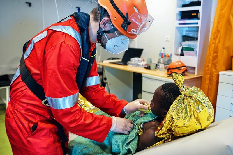 Member of the German charity Sea-Eye 4 takes care of a young migrant after a rescue operation in the Mediterranean Sea, May 16, 2021. The charity said it rescued 172 migrants from wooden boats during two rescue operations on Sunday. Picture taken May 16, 2021. Guillaume Duez/Sea-Eye/Handout via REUTERS ATTENTION EDITORS - THIS IMAGE HAS BEEN SUPPLIED BY A THIRD PARTY. MANDATORY CREDIT