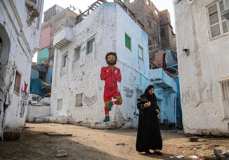 A woman walks past a mural depicting Liverpool's Egyptian striker Mohamed Salah in Cairo.  EPA