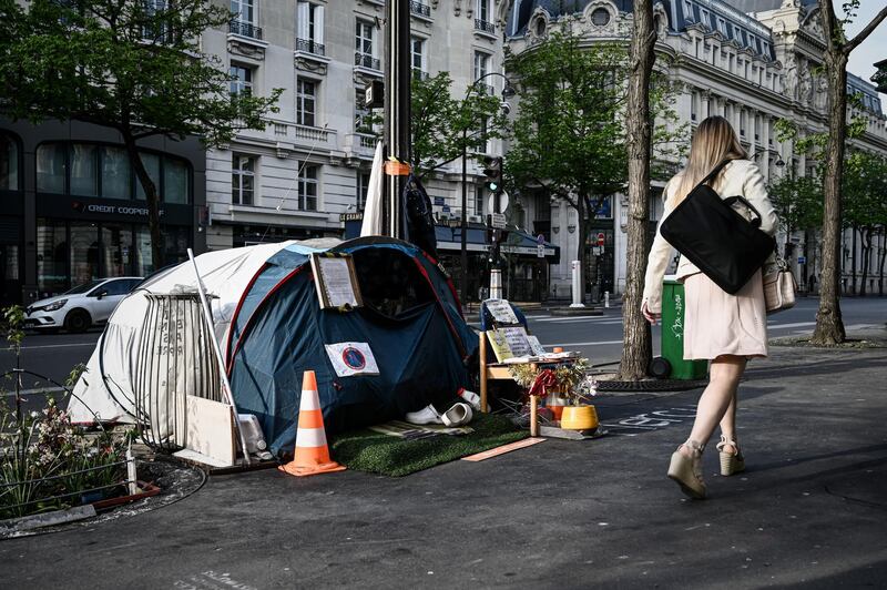 A woman walks past the tent of a homeless set up on the pavement in Paris on April 16, 2020 on the 31th day of a lockdown in France aimed at curbing the spread of the COVID-19 pandemic, caused by the novel coronavirus. (Photo by Philippe LOPEZ / AFP)