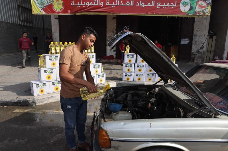 A Palestinian man funnels cooking oil into the engine of his car in Rafah in the southern Gaza Strip. AFP