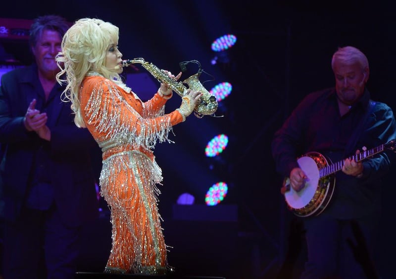 Dolly Parton, in statement orange, performs during a concert to benefit her Imagination Library at The University of Tennessee's Thompson-Boling Arena on May 28, 2014 in Knoxville, Tennessee. AFP