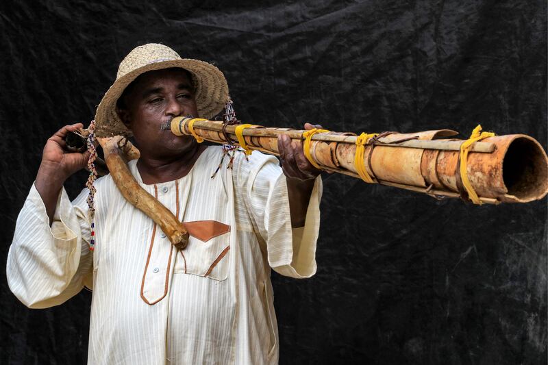 Dr Dafallah al-Haj Ali Mustafa, 51, founder and general director of the Sudanese Traditional Music Centre and assistant professor of music and drama, plays a traditional "Wazza" instrument at the centre in the Sudanese capital's twin city of Omdurman on September 10, 2022.  - Near the lush fields of his village in Sudan's southern Blue Nile state, locals have crafted a traditional horn-like instrument used for generations to usher in the harvest season.  Across the Blue Nile State communities, the instruments are used to celebrate the harvest season, which typically begins in November after the wet season.  (Photo by ASHRAF SHAZLY  /  AFP)