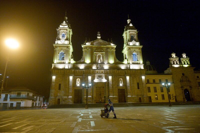 A worker walks down the Bolivar square in Bogota, on January 13, 2021, during a Covid-19 lockdown. - Half of the population of Bogota (over four million people) will remain under strict lockdown until Sunday January 17 as a measure to stop the spread of the Covid-19 as the capital has experienced a sharp rise in infections, Mayor Claudia Lopez announced. (Photo by Raul ARBOLEDA / AFP)