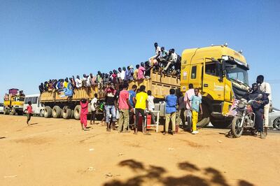 People displaced by the conflict in Sudan get on top of the back of a truck moving along a road in Wad Madani AFP