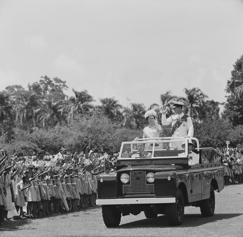 Queen Elizabeth II and Prince Philip, Duke of Edinburgh pictured waving to crowds of cheering school children from the rear of an open top Land Rover car outside Government House during a Commonwealth visit to Fiji on 2nd February 1963. (Photo by Daily Express/Hulton Archive/Getty Images)