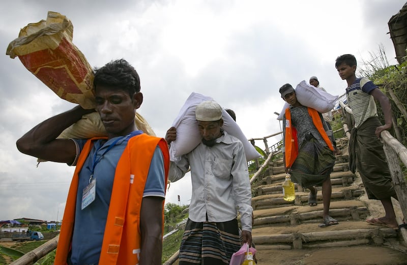 Refugees walk with food donations in a camp in Cox's Bazar. Getty Images