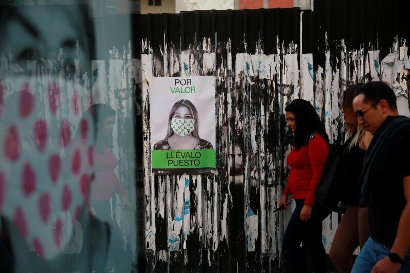 People walk past a poster to raise awareness about wearing a face mask, as the coronavirus disease (COVID-19) outbreak continues, in Mexico City, Mexico. The poster reads: "For courage, wear it" REUTERS