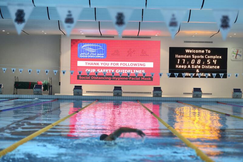 Dubai, United Arab Emirates - Reporter: N/A. News. Coronavirus/Covid-19. Swimmers in the pool under a large safety sign about Covid-19 at Hamdan sports complex. Monday, November 2nd, 2020. Dubai. Chris Whiteoak / The National