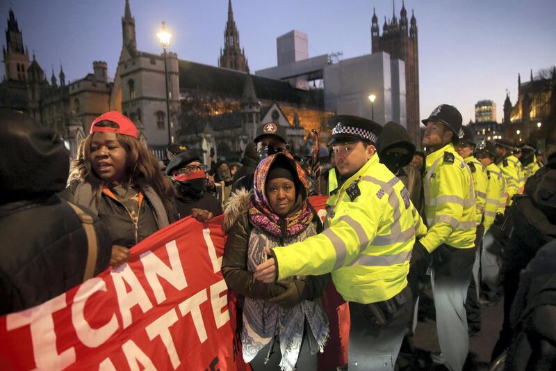 Police marshall protestors during a demonstration against slavery and pro-human rights organised by the'African Lives Matter' movement as they block traffic near the Houses of Parliament in central London on December 18, 2017.  / AFP PHOTO / Daniel LEAL-OLIVAS
