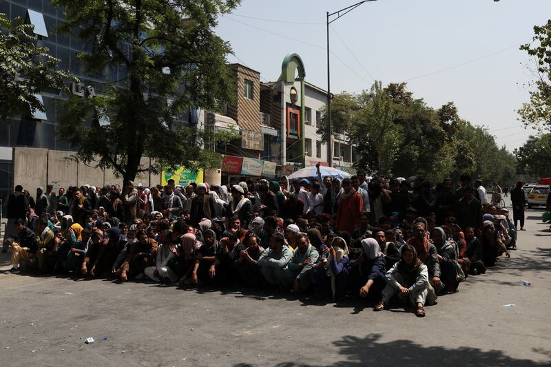 Customers wait outside a bank on a street in Kabul, Afghanistan. Reuters