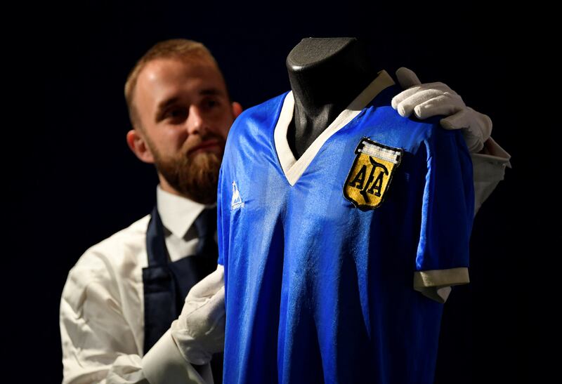 A Sotheby's art handler poses with the shirt worn by the late Argentinian great Diego Maradona during the 1986 World Cup, ahead of it being auctioned by Sotheby's in London on Wednesday, April 20, 2022. Reuters