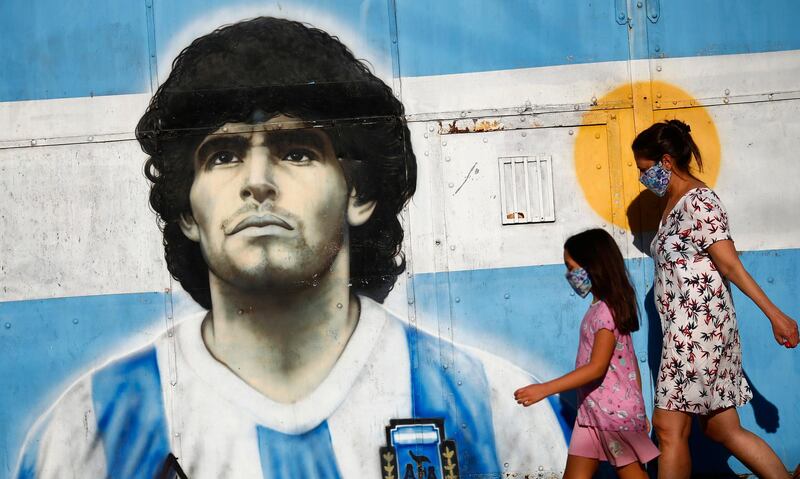 A woman and a girl walk by a mural of Maradona in  Buenos Aires. Getty