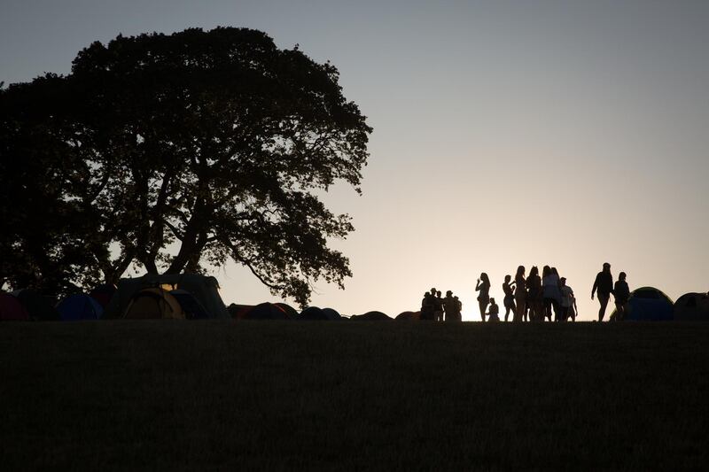 Festival goers walk around the camping fields as the sun sets at Bestival, at Lulworth Castle in Dorset, England. Getty Images