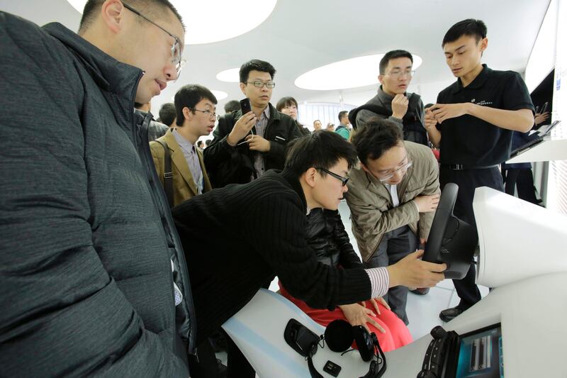 Visitors watch the steering system simulator at the Shanghai International Automobile Industry Exhibition (AUTO Shanghai) in Shanghai, China Sunday, April 21, 2013. (AP Photo/Eugene Hoshiko) *** Local Caption ***  China Auto Show.JPEG-051e9.jpg