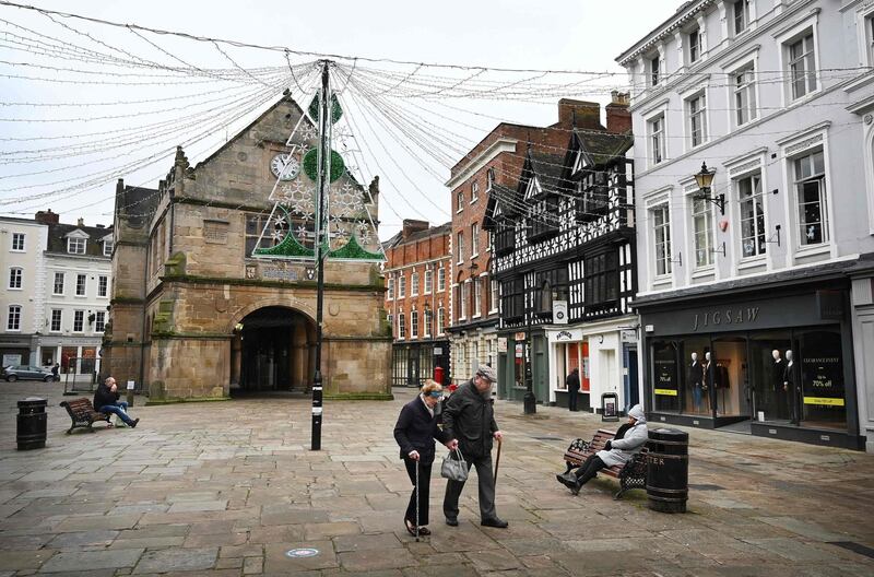 People wearing face shields walk past closed shops in Shrewsbury, western England. AFP