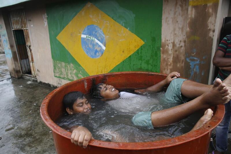 Children bathe in a roof top water tank, in front of a wall paint with the flag of 2014 World Cup host Brazil, in Dhaka. Millions of Bangladeshi football fans mostly support the national football teams of Argentina and Brazil. Andrew Biraj / Reuters