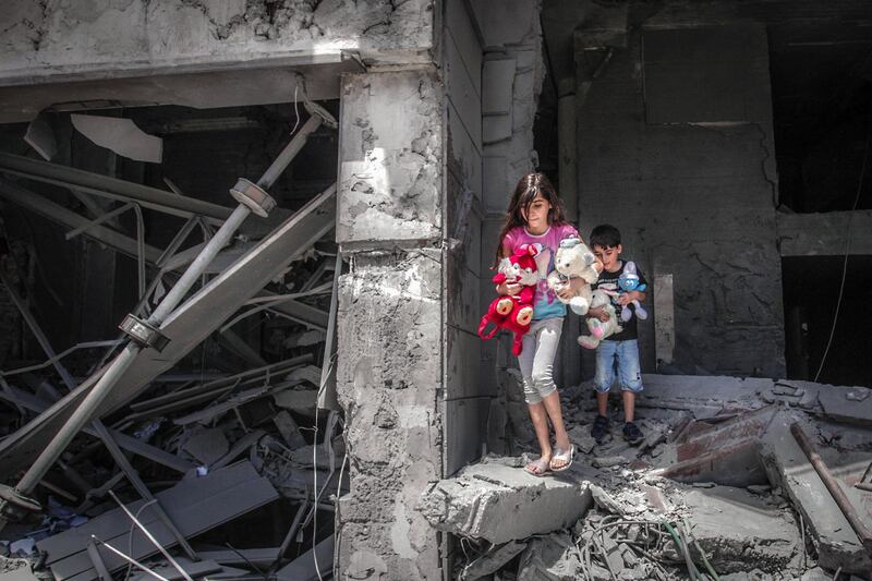 TOPSHOT - Palestinian children salvage toys from their home at the Al-Jawhara Tower in Gaza City, on May 17, 2021, which was heavily damaged in Israeli airstrikes. / AFP / ANAS BABA
