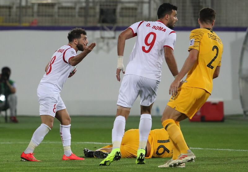 Syria's Mahmoud Al Mawas reacts to a yellow card as Australia's Aziz Behich lies on the pitch. AFP