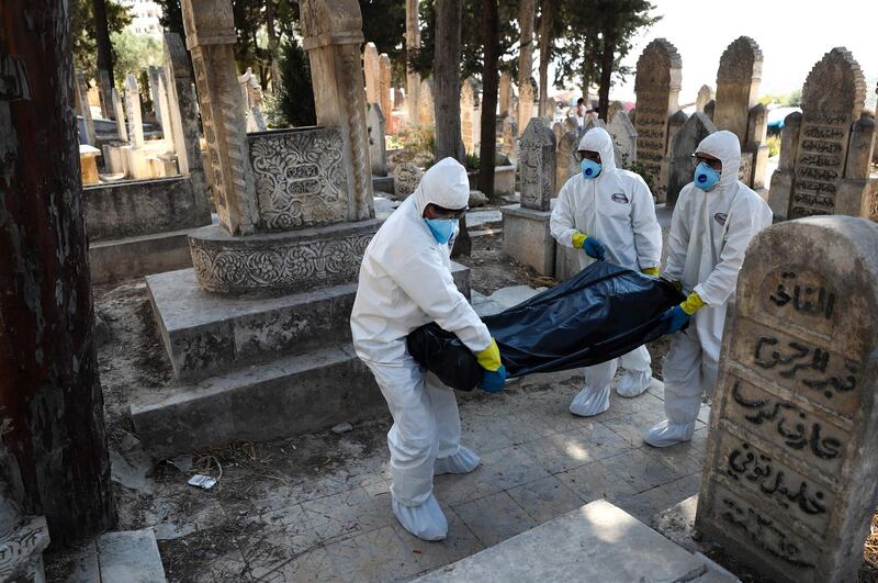 Health workers wearing protective jumpsuits carry the body of a 62-year-old displaced Syrian man who died from Covid-19 in Salqin, in the northwestern Syrian Idlib province. AFP