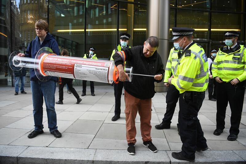 epa08839318 Anti-vax demonstrators talks to police as they hold a large syringe while protesting against Covid-19 vaccination, outside the headquarters of the Bill and Melinda Gates Foundation in London, Britain, 24 November 2020. Vaccine trials from a number of pharmaceutical companies are proving successful, giving hope at ending restrictions due to the ongoing coronavirus pandemic.  EPA-EFE/NEIL HALL *** Local Caption *** 56518024