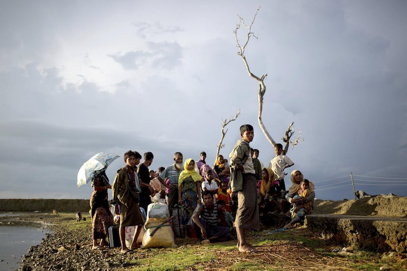 A group of Rohingya refugees who reached the Bangladesh mainland overnight, wait at sunrise to be allowed access to an official registration centre.