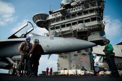 FILE - In this June 3, 2019 file photo, a pilot speaks to a crew member by an F/A-18 fighter jet on the deck of the USS Abraham Lincoln aircraft carrier in the Arabian Sea.  As Iran prepares to break through limits set by its 2015 nuclear deal with world powers, each step narrows the time its leaders would need to have enough highly enriched uranium for an atomic bomb -- if they chose to build one. By Thursday, June 27, 2019, Iran says it will have over 300 kilograms of low-enriched uranium in its possession, which would mean it had broken out of the atomic accord. (AP Photo/Jon Gambrell, File)