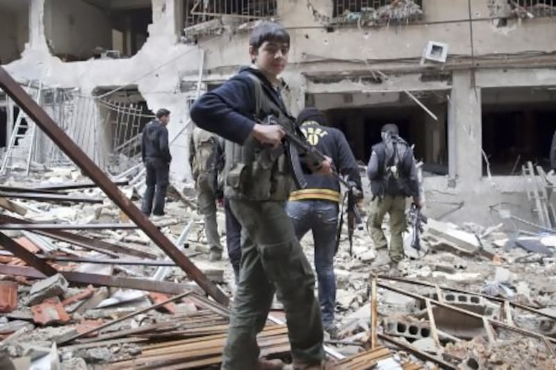 A Free Syrian Army fighter in front of a building destroyed during clashes in the Haresta neighbourhood of Damascus.