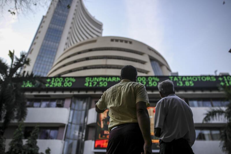 Pedestrians look up at an electronic screen and a digital ticker board at the Bombay Stock Exchange (BSE) building in Mumbai, India, on Monday, Feb. 3, 2020. Indian Prime Minister Narendra Modi’s government plans to allow foreign investors greater access to short-term and long-term government securities in a bid to tap money being poured into passive funds operated by firms such as BlackRock Inc. Photographer: Dhiraj Singh/Bloomberg