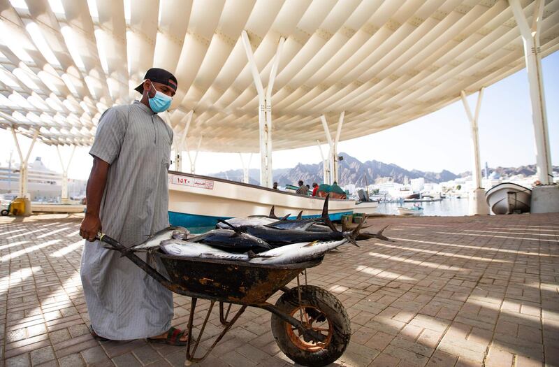 A vendor wearing a face mask against the coronavirus uses a wheelbarrow to carry fresh fish to be sold at the Mutrah Souq in the Omani capital Muscat on September 18, 2020.  / AFP / Haitham AL-SHUKAIRI
