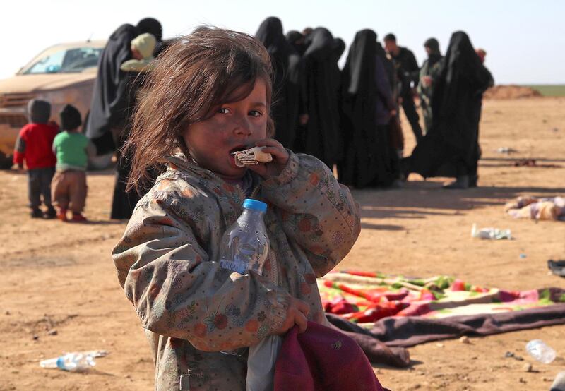 A child nibbles on a piece of bread as civilians fleeing from fighting between Syrian Democratic Forces (SDF) and Islamic State (IS) jihadists in the frontline Syrian village of Baghuz, await to be screened and registered by the SDF in the countryside of the eastern Syrian Deir Ezzor province on January 31, 2019. (Photo by Delil SOULEIMAN / AFP)