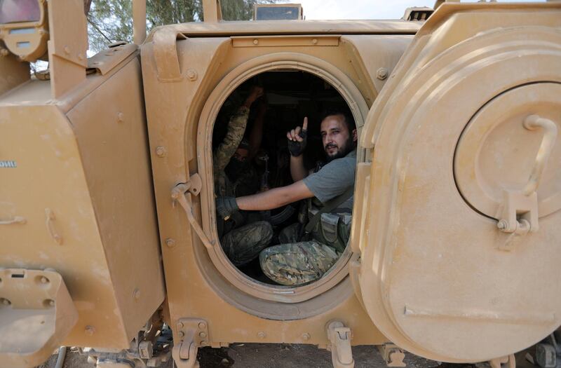 A Turkey-backed Syrian rebel gestures as they drive their military tank near the border town of Tal Abyad. Reuters